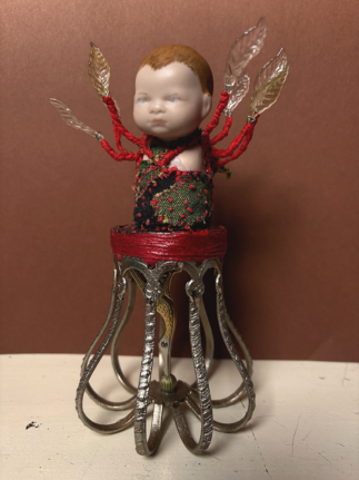 Deity talisman for evoking vitality and life force, made from found objects, fabric, clay and ceramic doll - approx. 24 x 10 x 10 cm Altar talisman of Mars, made from found objects and a ceramic doll body. Evoking the vitality and life force from above